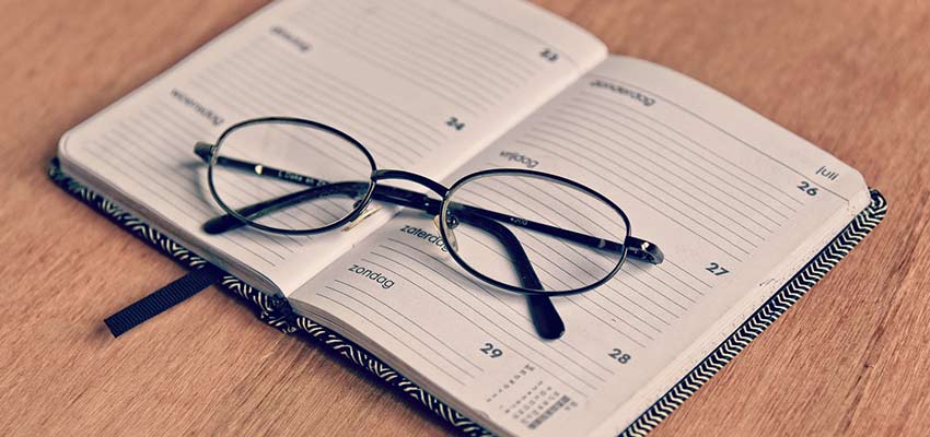 A pair of glasses on top of a planner.