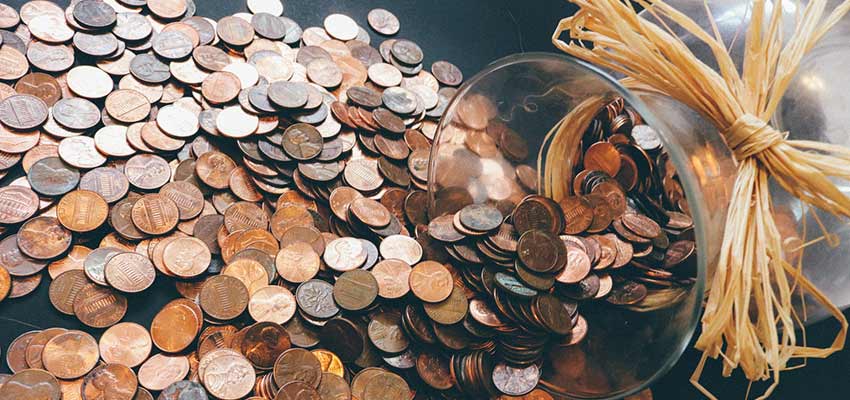 A jar of pennies spilled on a table.