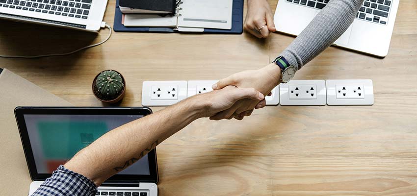 People shaking hands across a desk.